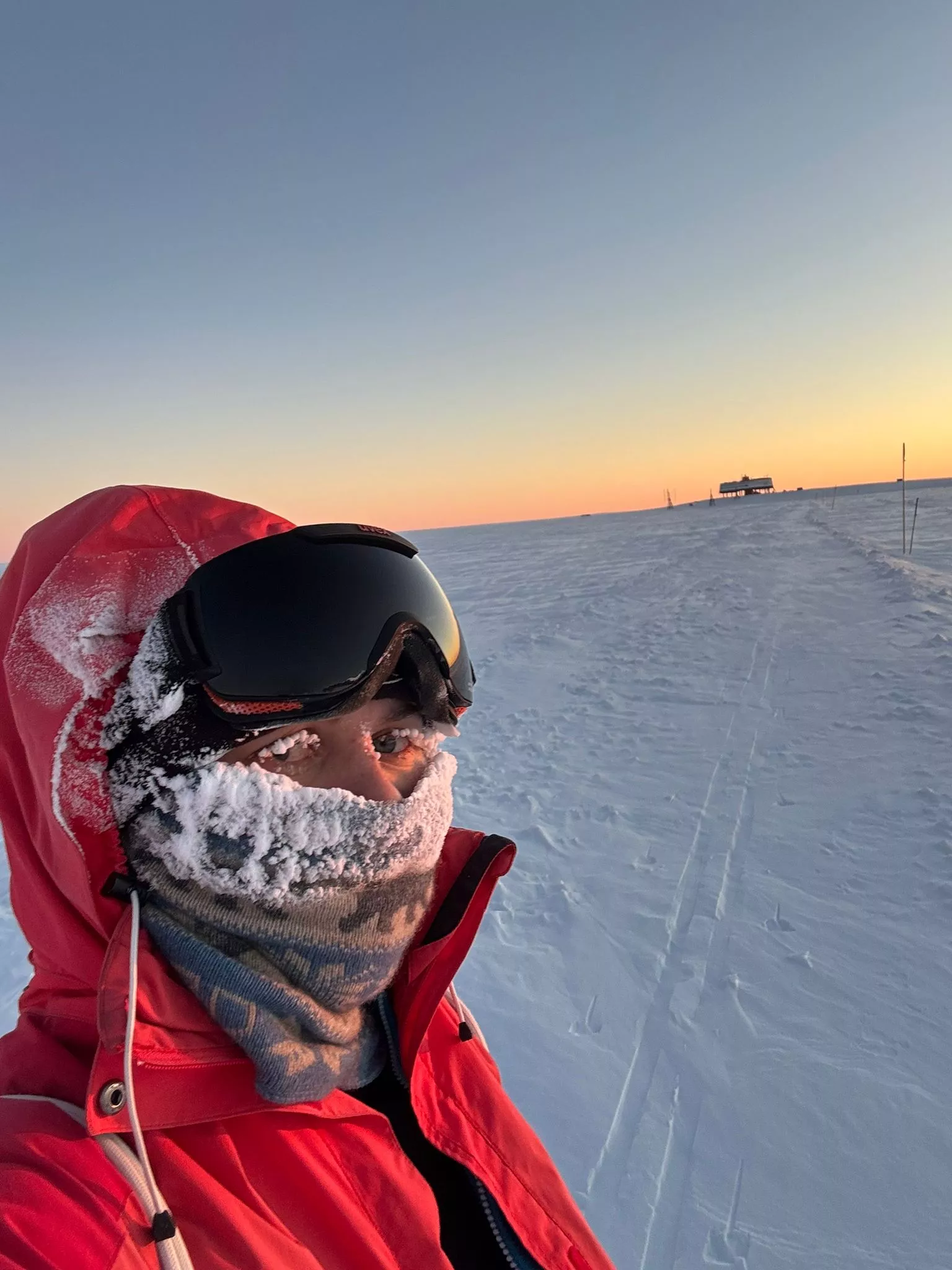 Forscherin in der Antarktis in einem roten Schneeanzug. Es ist so kalt, dass sogar ihre Wimpern gefroren sind.